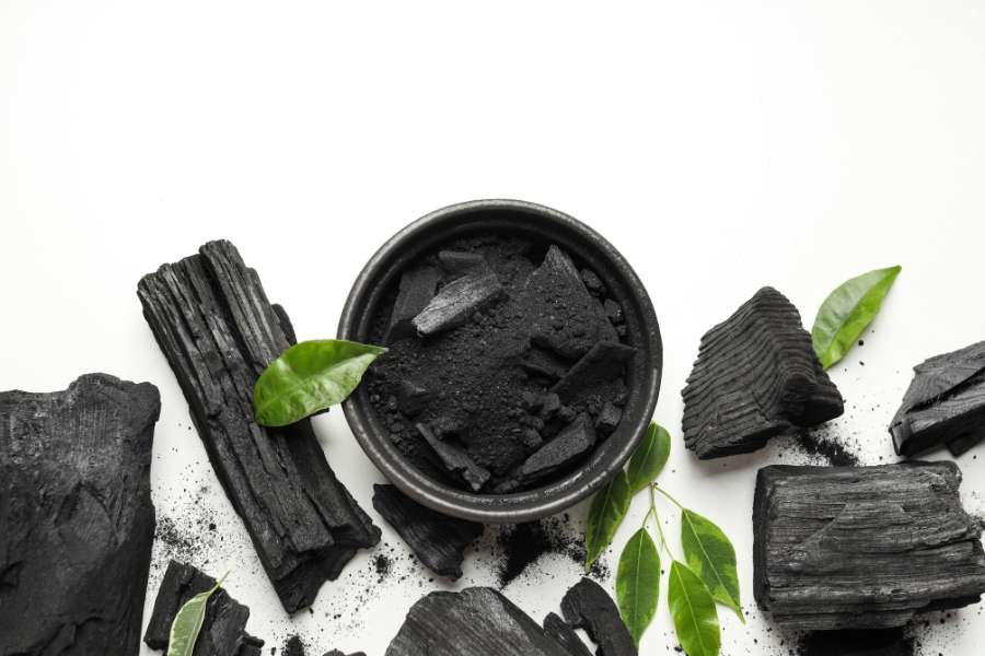 Bol de charbon actif végétal et morceaux de bois.